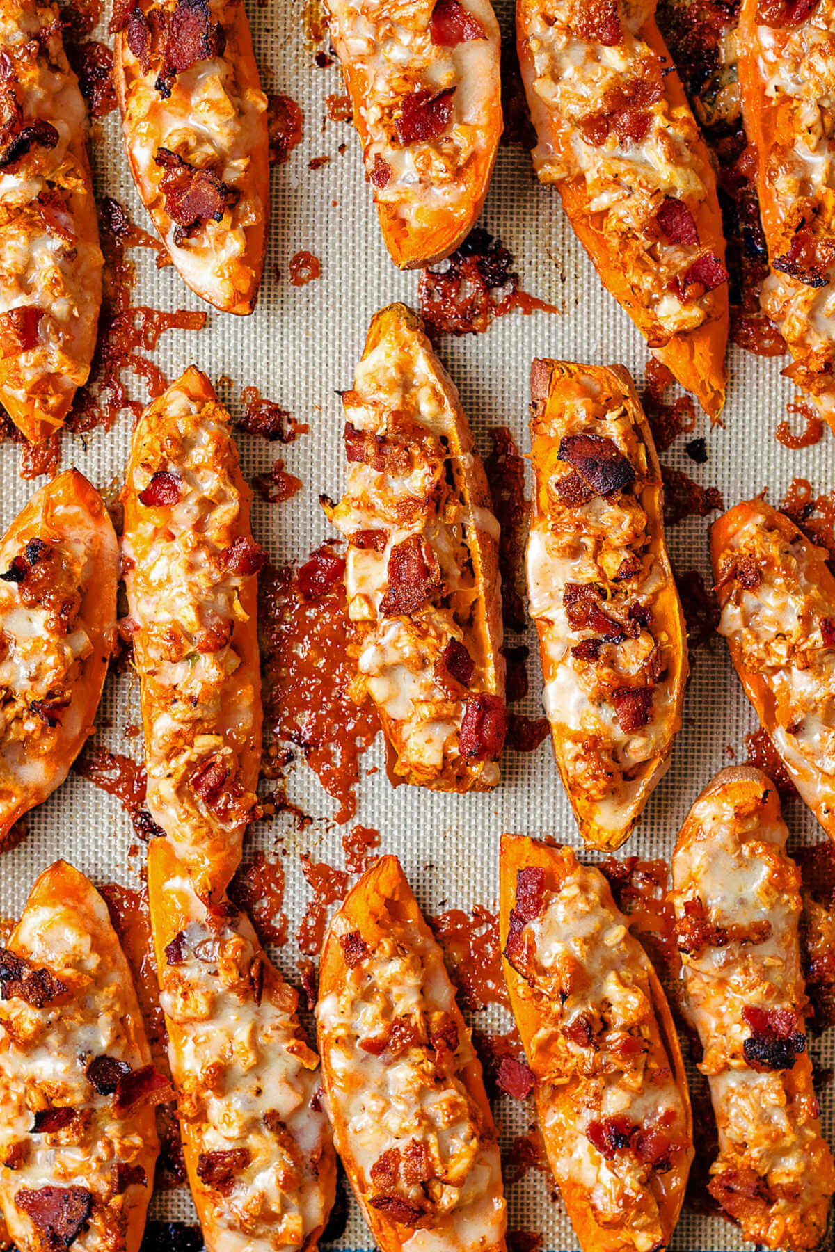 loaded sweet potato skins on a baking mat with melted cheese.