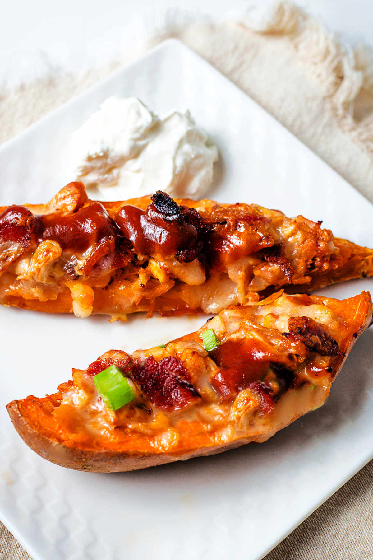 two sweet potato skins on a plate with a dollop of sour cream.