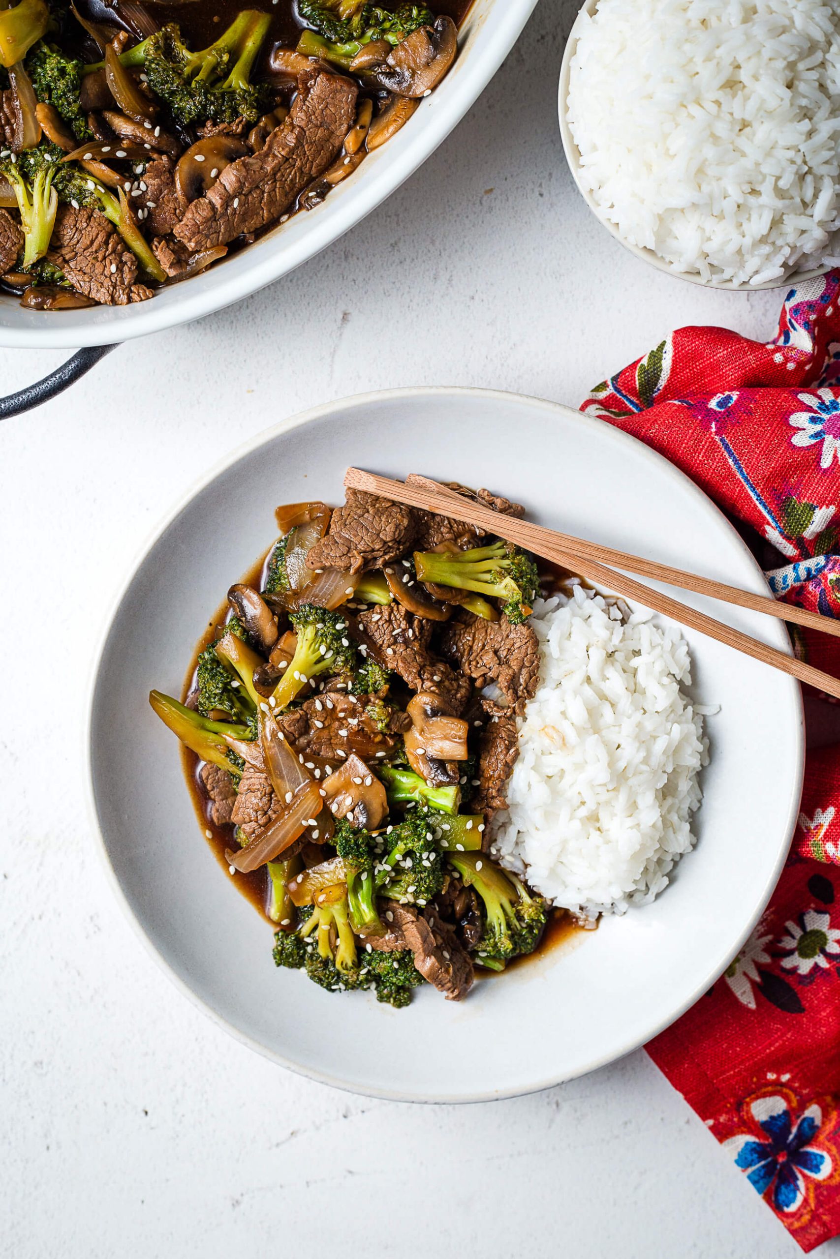 beef and broccoli in a bowl with rice and chopsticks.