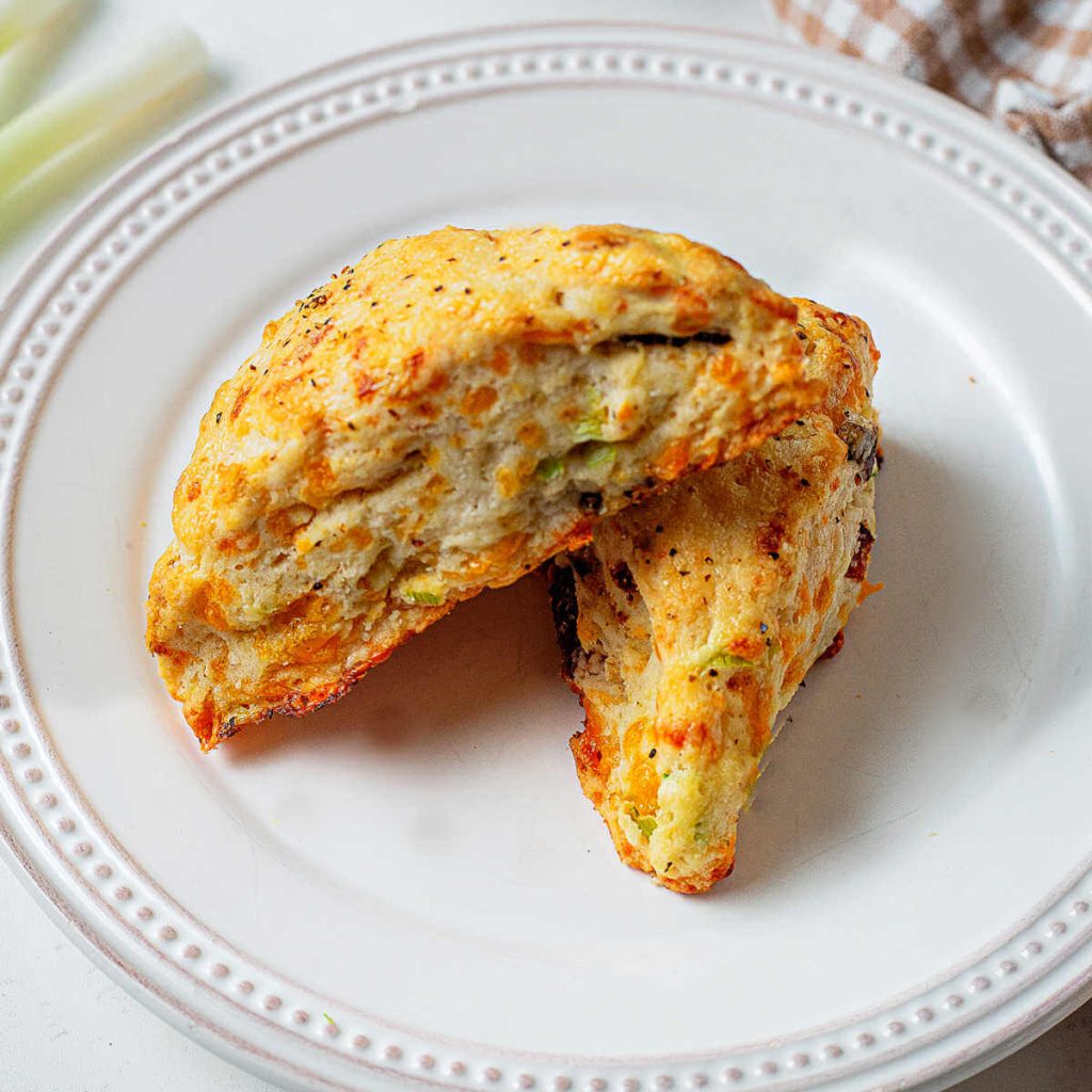 Two bacon cheddar scones on a plate.