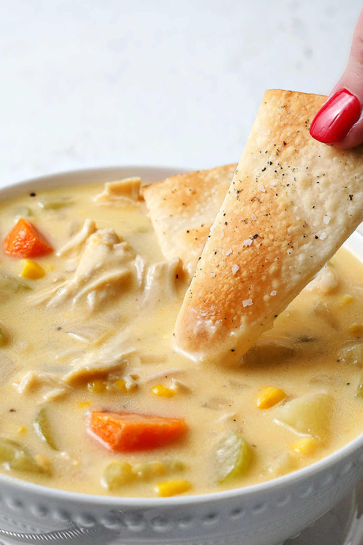 dipping a pie crust cracker into a bowl of chicken pot pie soup.