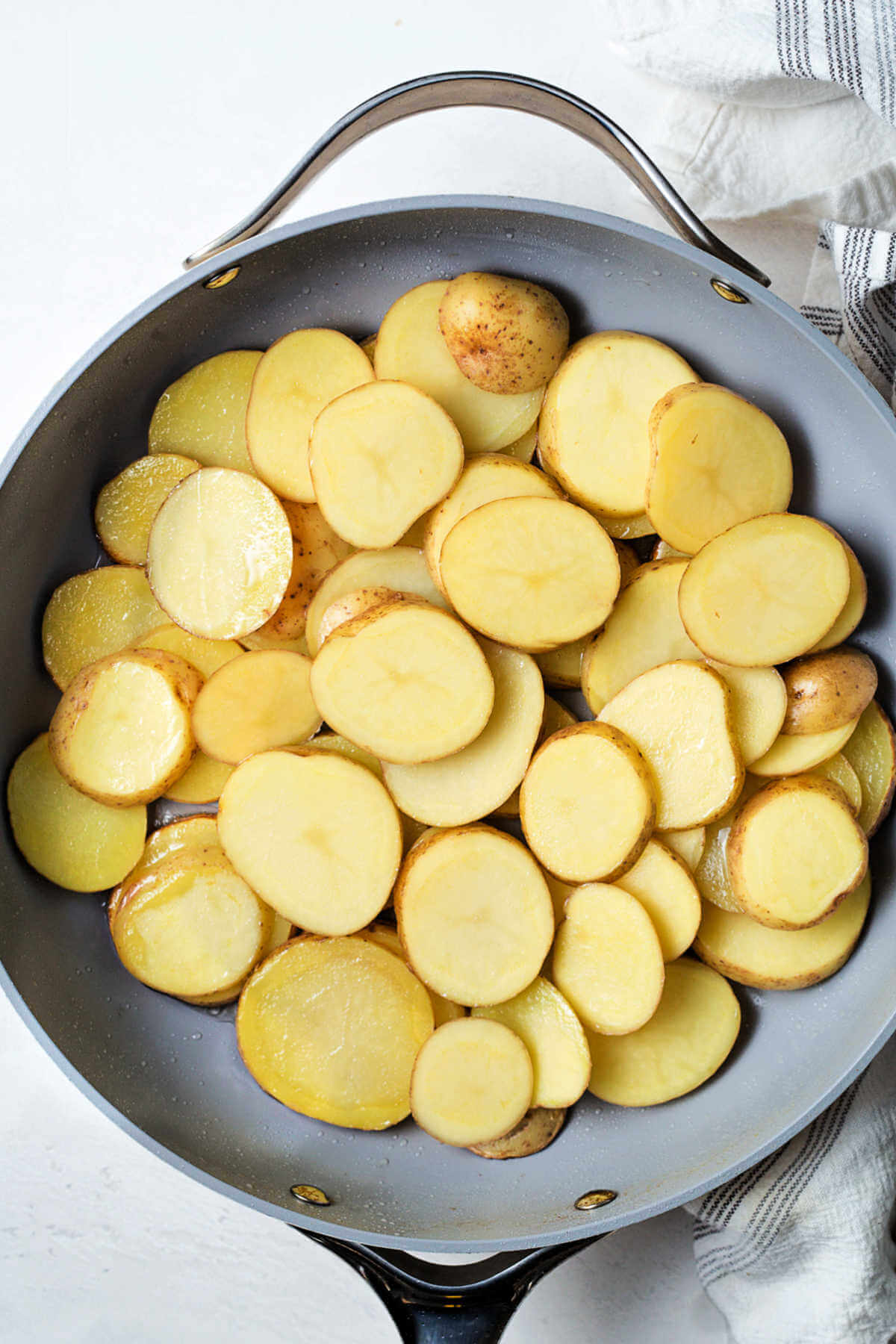 sliced potatoes layered in a large skillet.