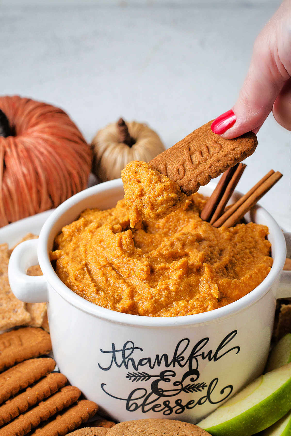 dipping a biscoff cookie into a bowl of pumpkin dip.