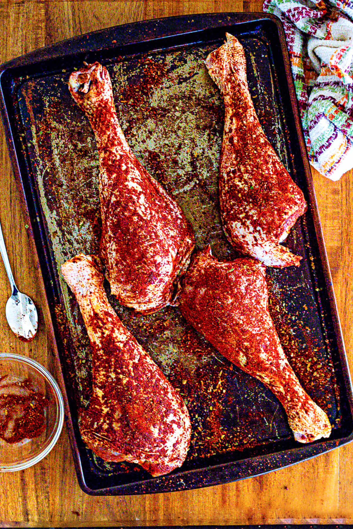 raw turkey legs with coated with dry rub on a baking sheet