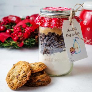 a jar of chocolate chip cookie mix on a table with a stack of cookies.