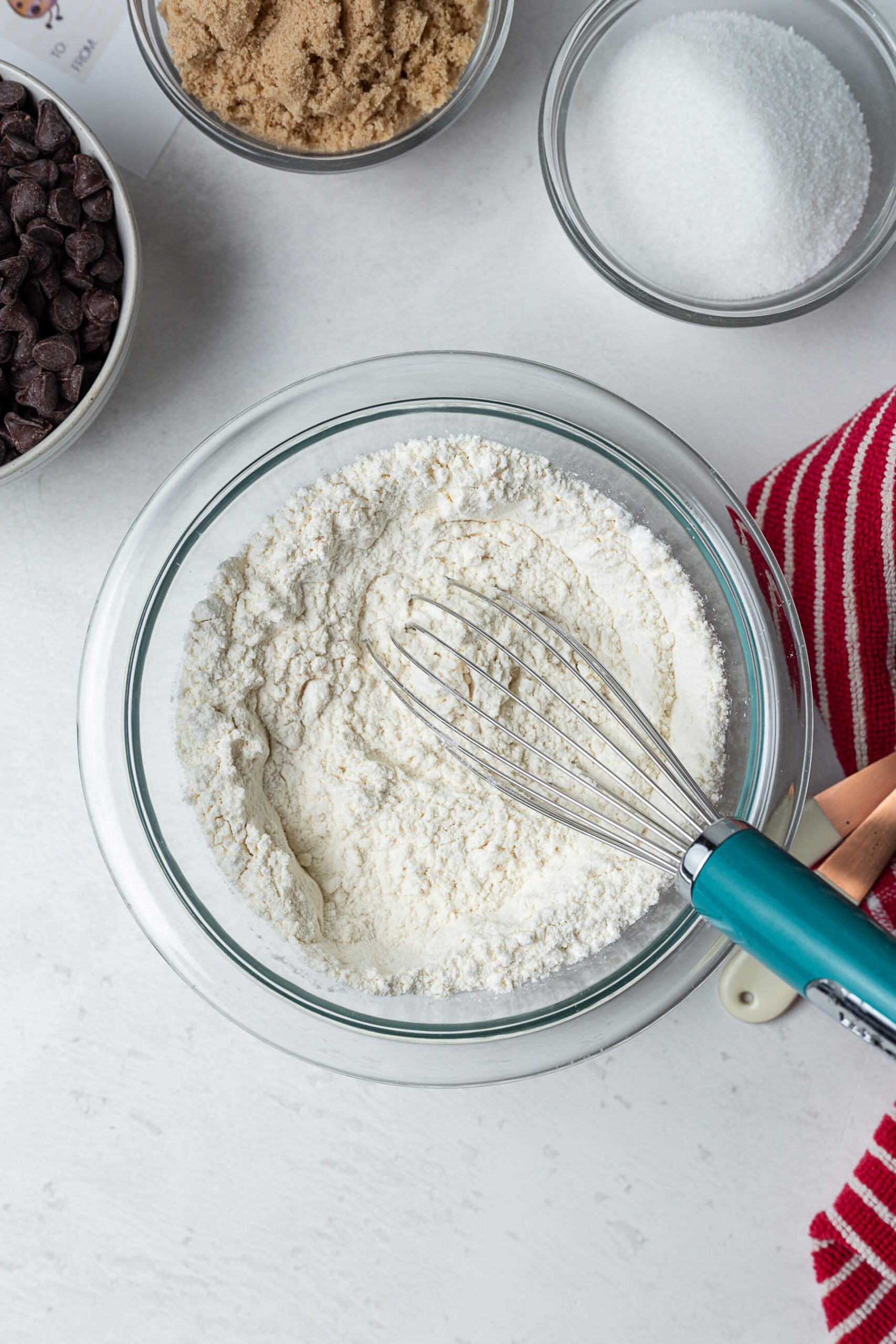whisking flour with baking soda and salt in a glass bowl.