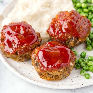 mini meatloaf muffins on a dinner plate on a table.