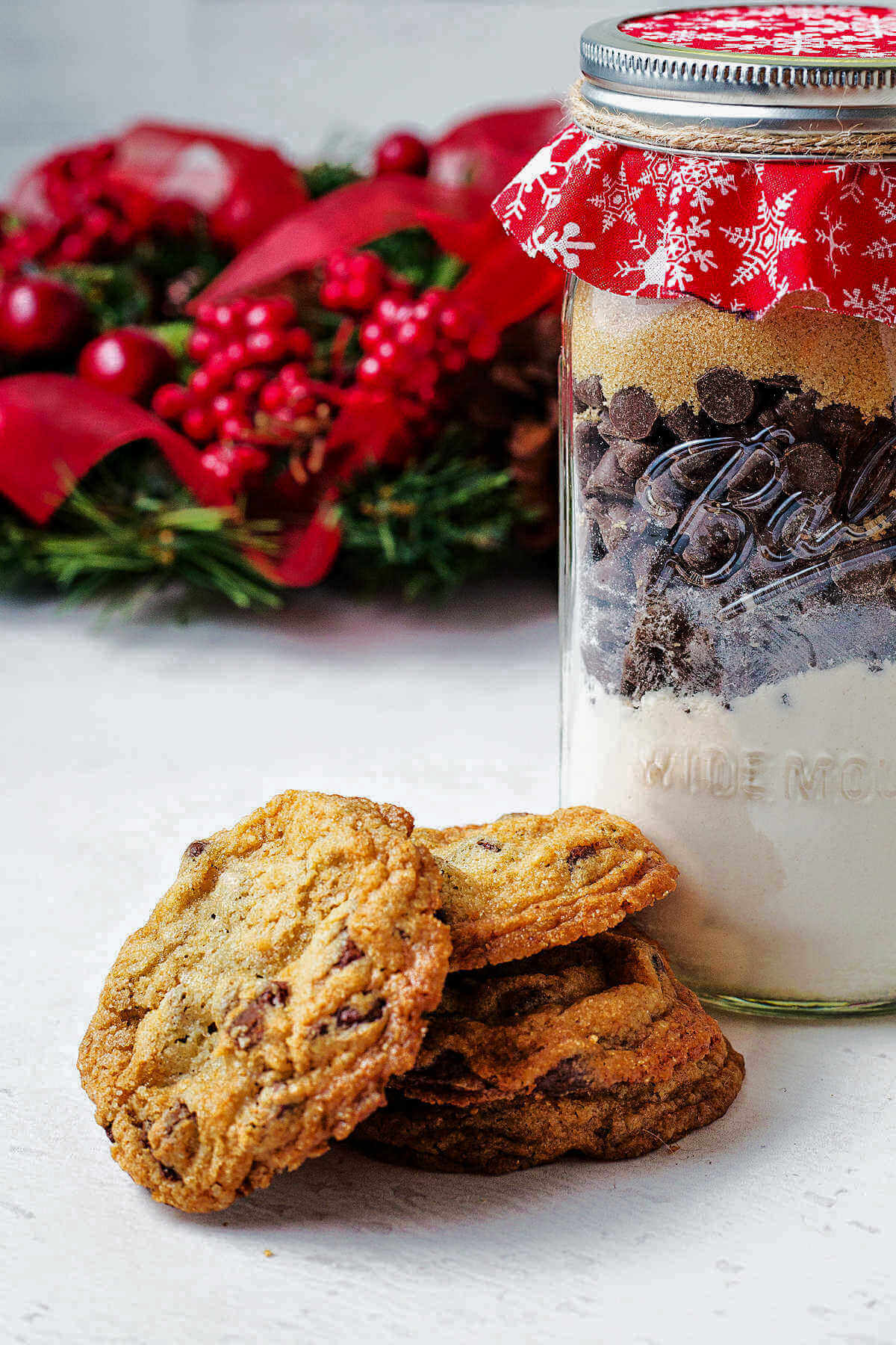 chocolate chip cookie mix in a jar on a table with a stack of cookies.