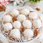 a plate of sand tart cookies on a table with holiday decor.