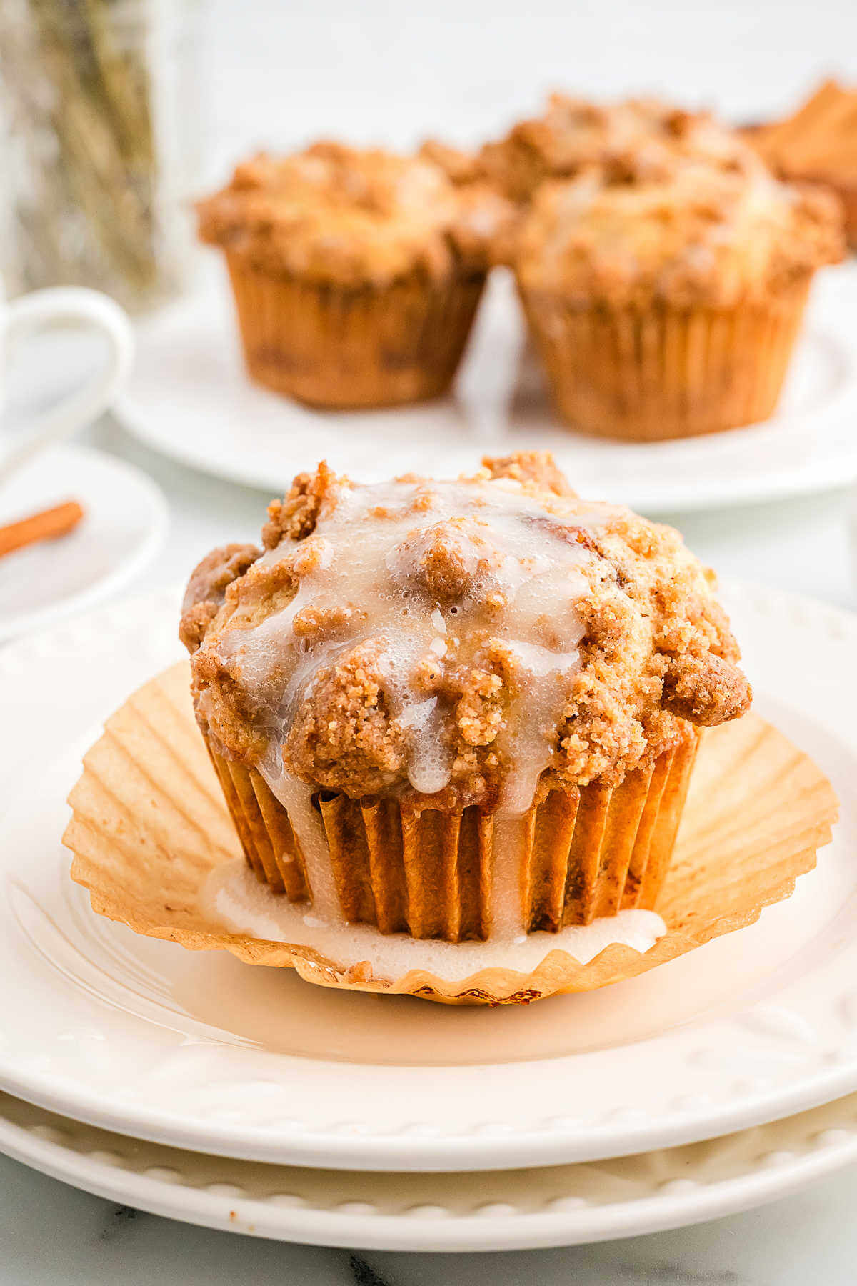 a vanilla iced coffee cake muffin on a serving plate on a table.