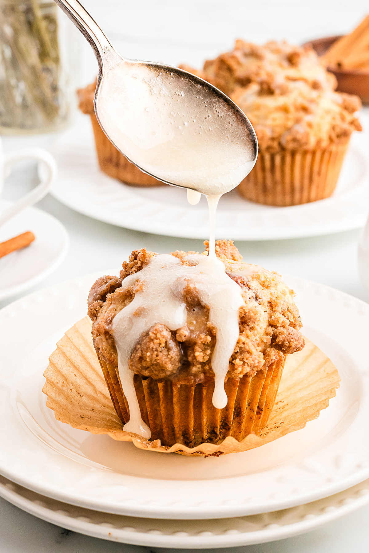 drizzling vanilla icing on top of a coffee cake muffin.