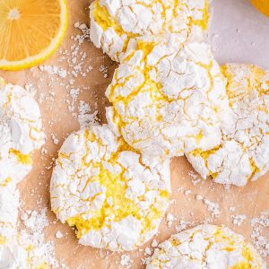 Lemon crinkle cookies with lemon slices on parchment paper.