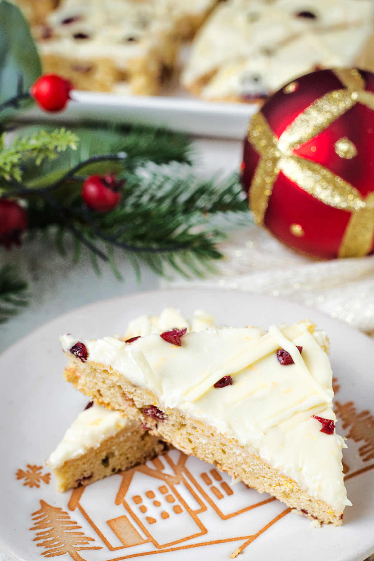 two cranberry bliss bars on a holiday serving plate on a table with Christmas decor.