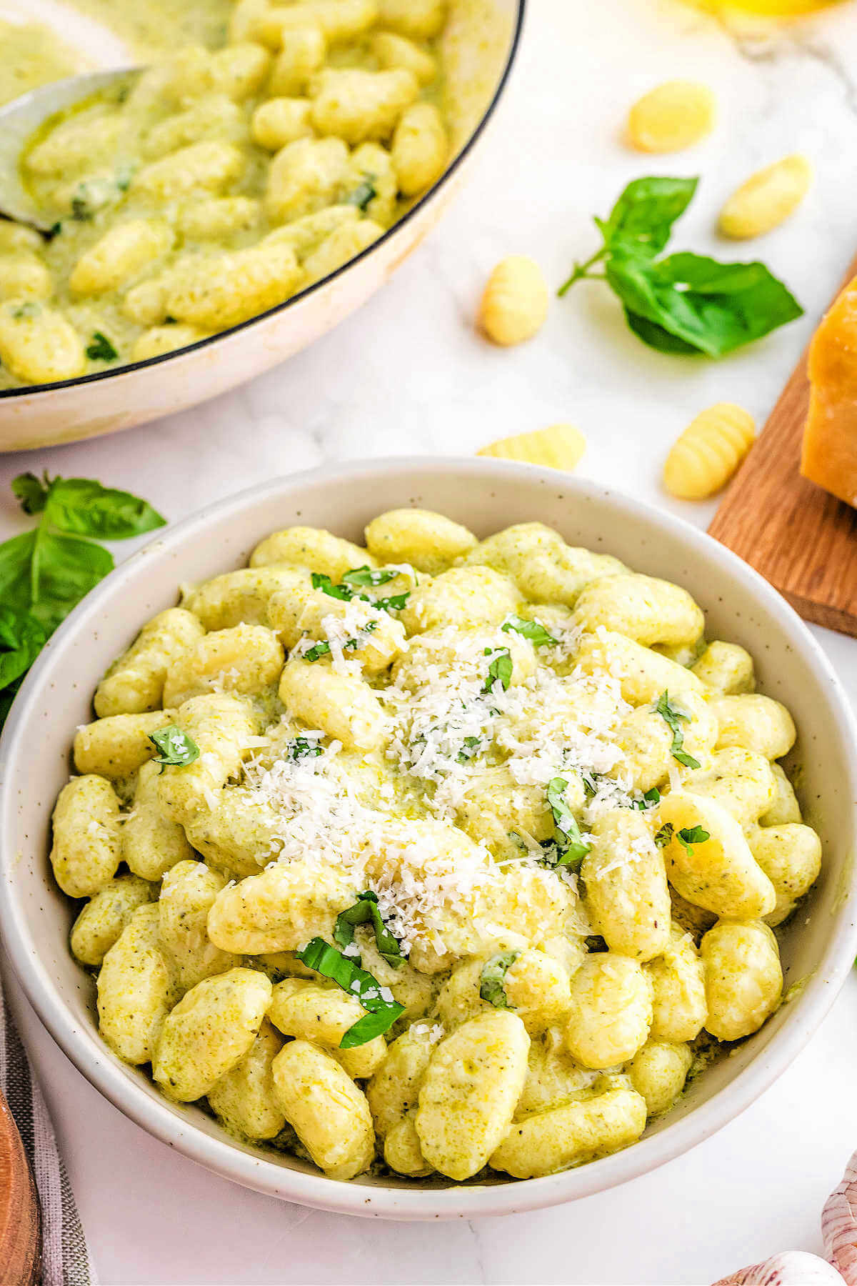 a serving of gnocchi with pesto sauce in a serving bowl on a table.