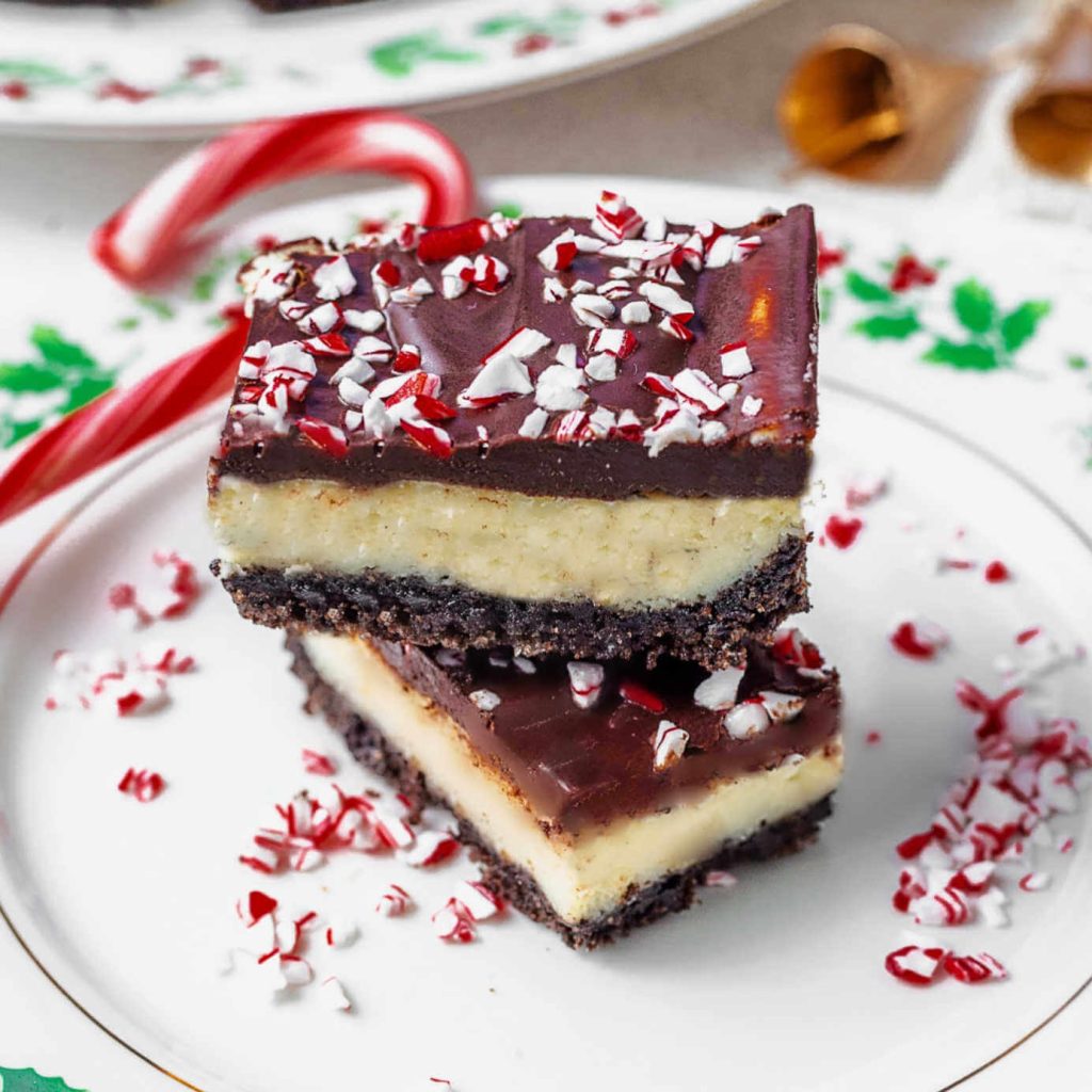 two peppermiint cheesecake bars on a china plate with candy cane bits.