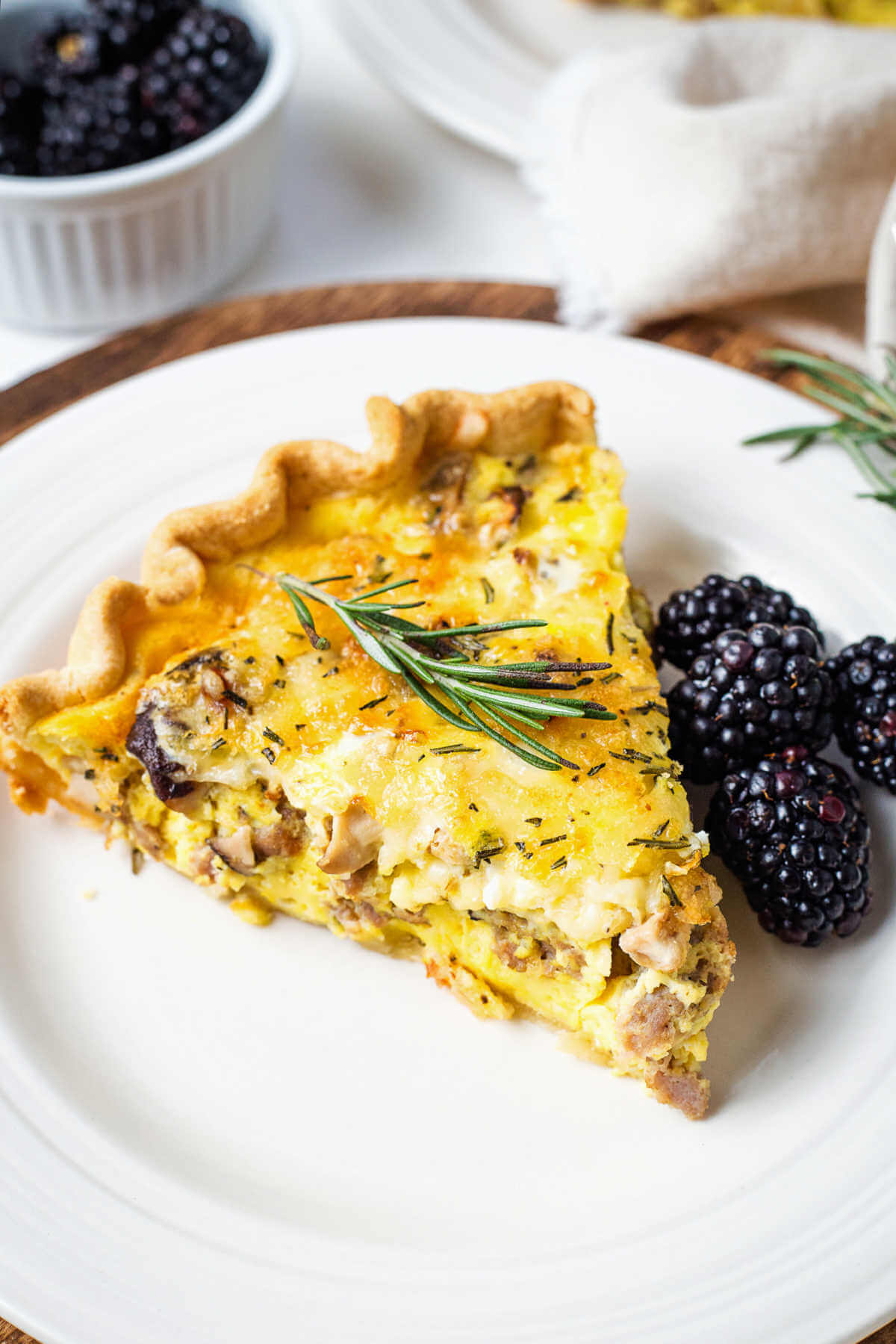 sausage quiche with blackberries on a plate on a table.