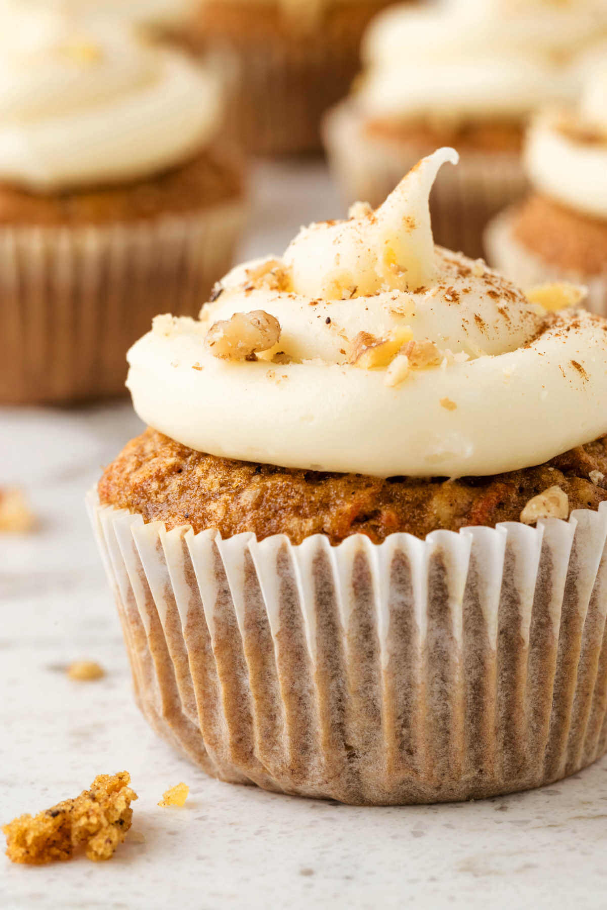 close up view of a frosted carrot cake muffin on a table.