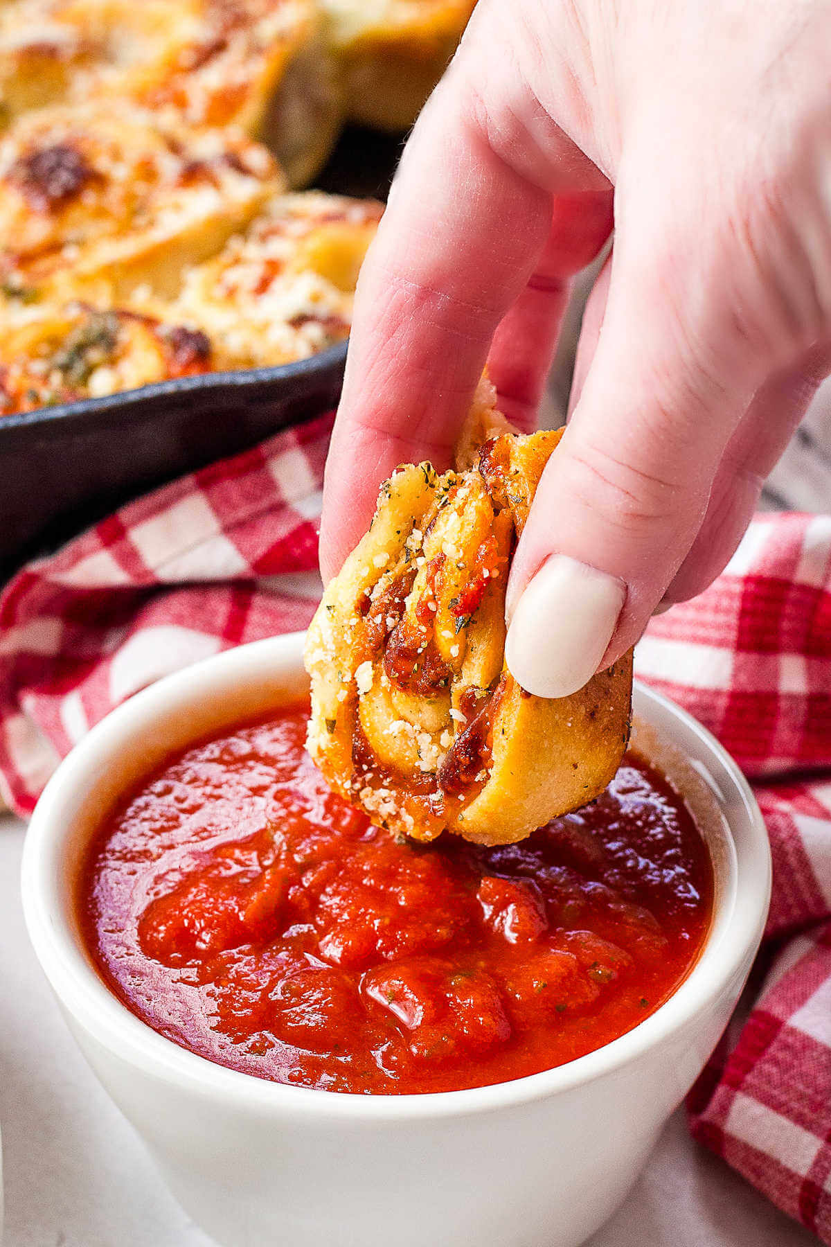 dipping a pizza roll into a bowl of marinara.