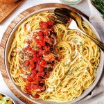 balsamic chicken sliced on top of a bed of spaghetti with extra sauce ladeled on top.