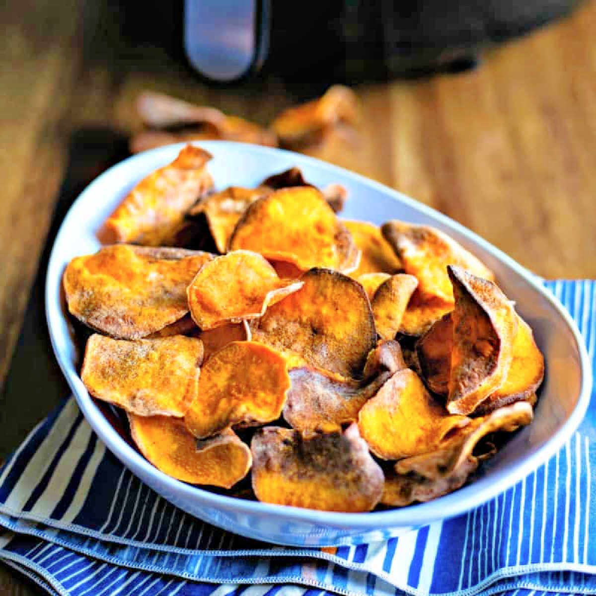 Air Fryer Sweet Potato Chips in a bowl on a napkin on a wooden table.