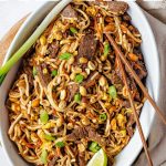 Beef Pad Thai with Crunchy Peanuts in a serving dish with chopsticks.