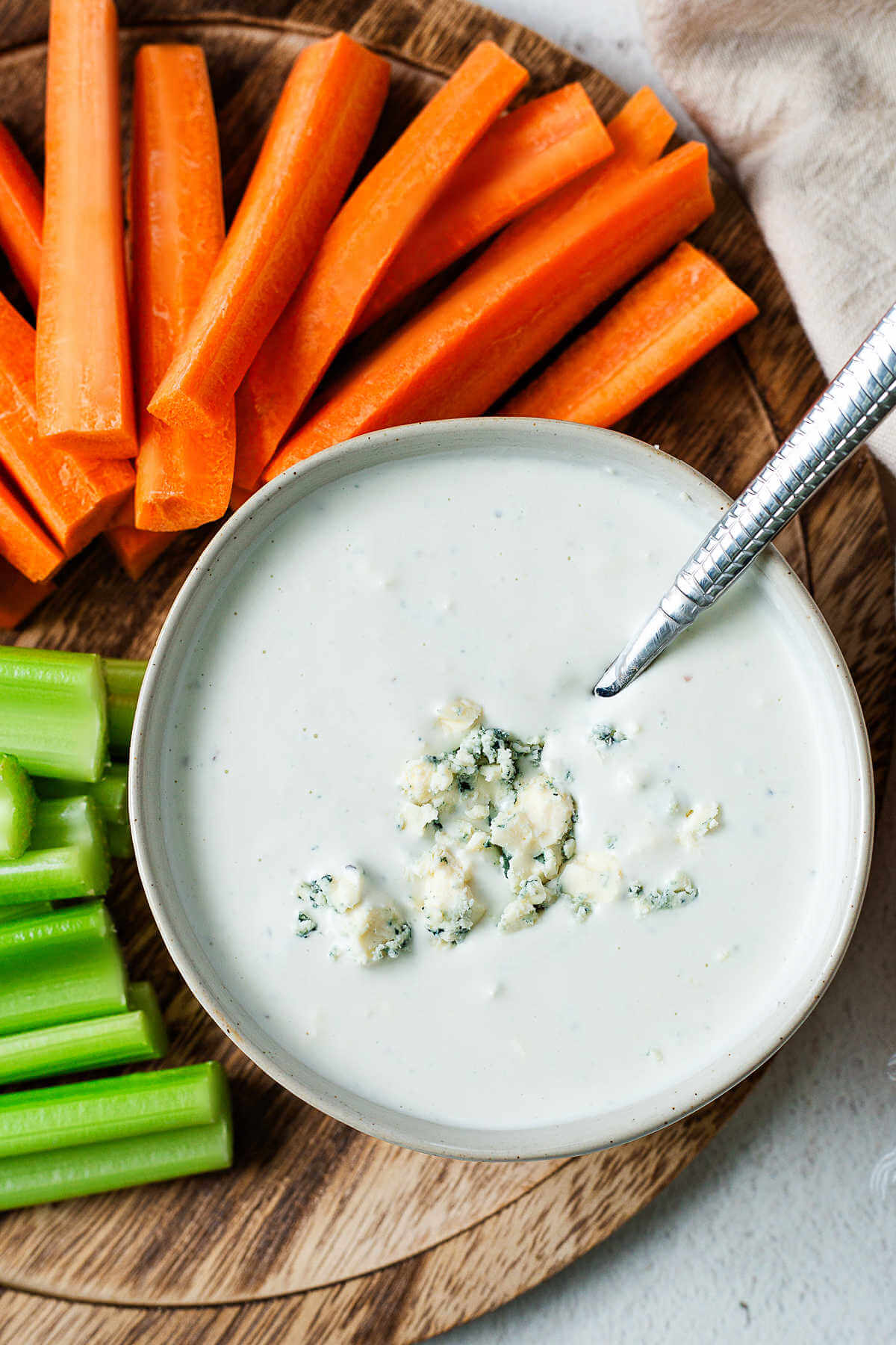 Blue cheese dressing in a bowl on a platter of carrot and celery sticks.