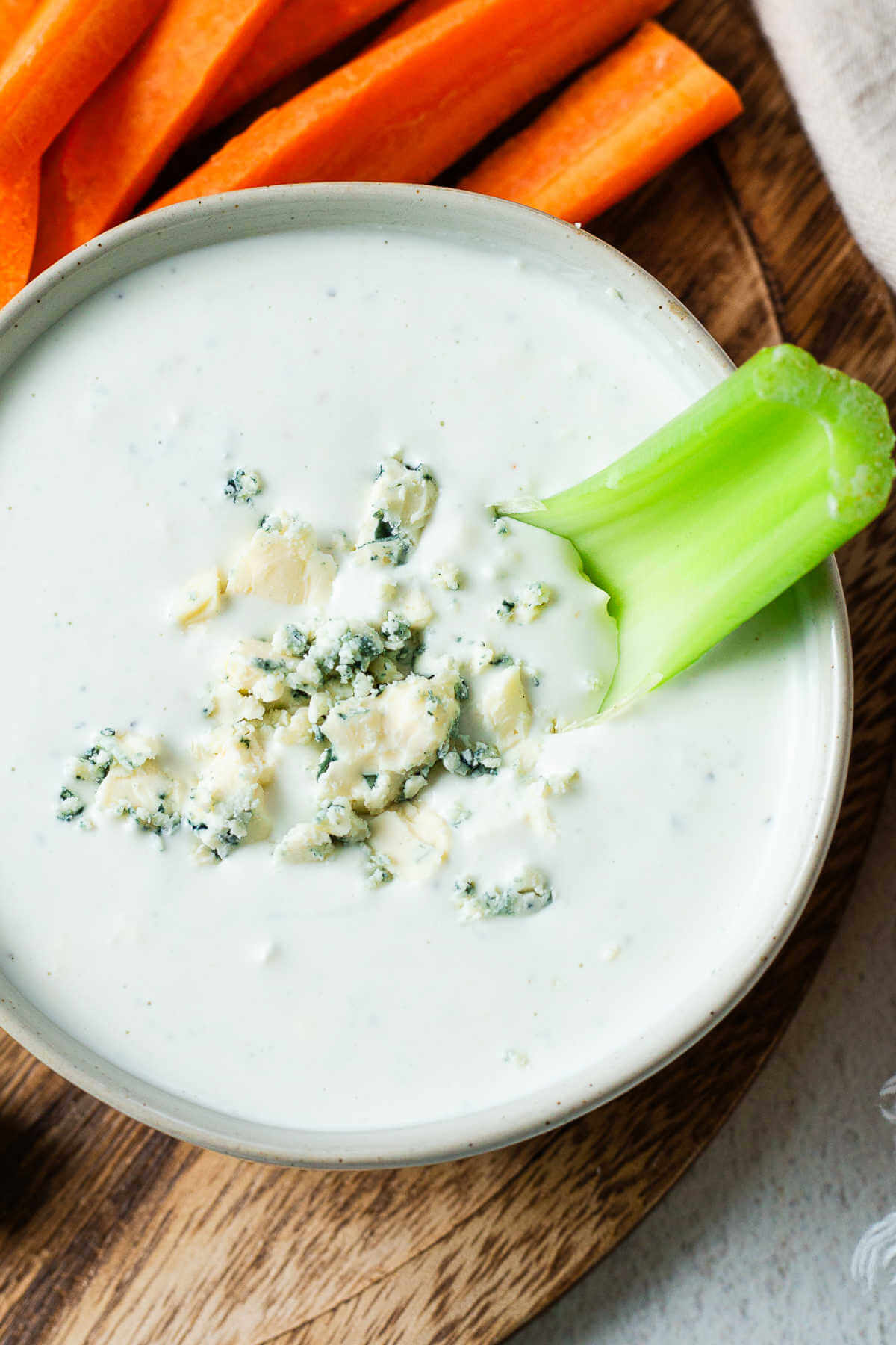 A celery stick dunked into a bowl of blue cheese dressing.