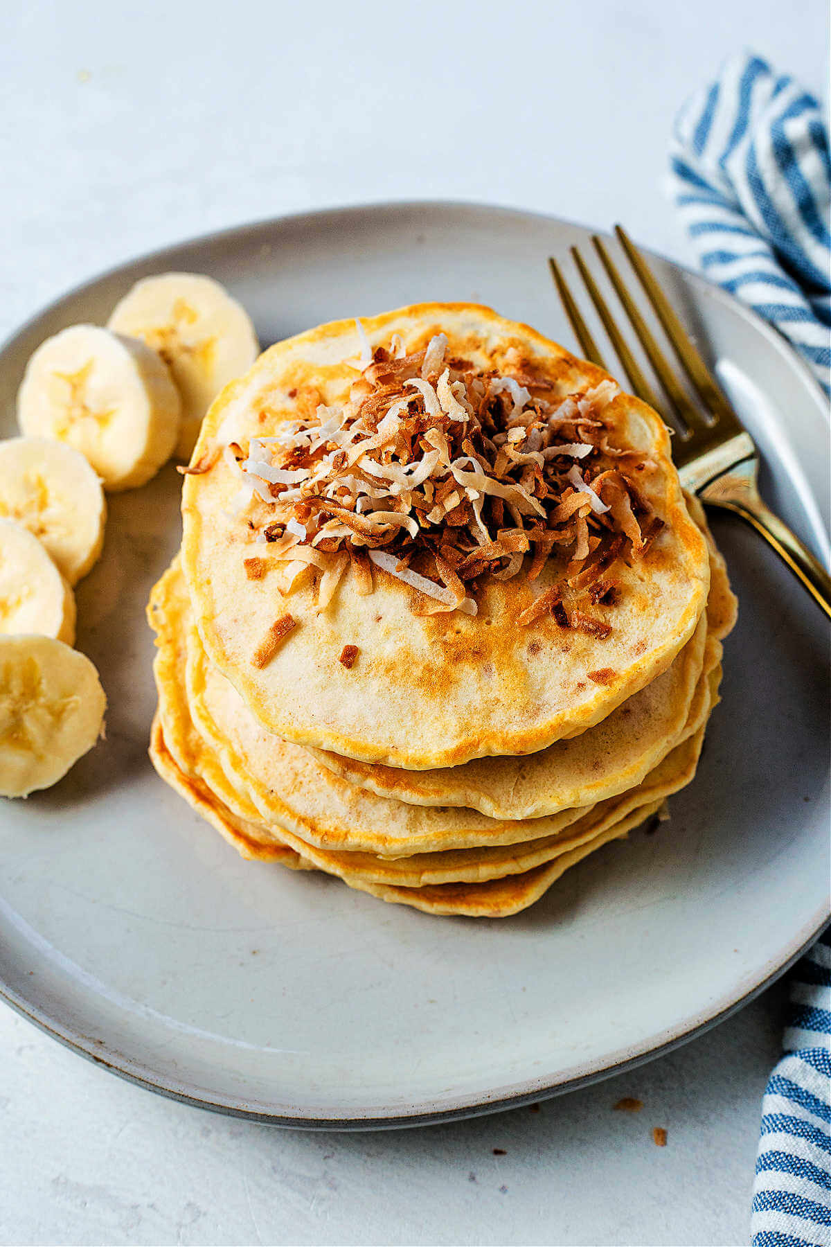 A freshly cooked stack of coconut pancakes on a plate on a table.
