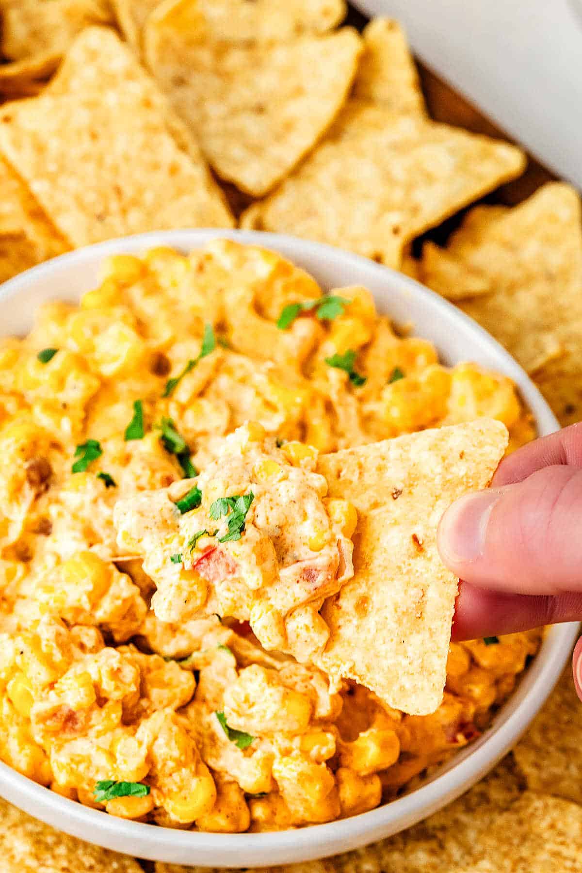 Dipping a chip into a bowl of hot corn dip.