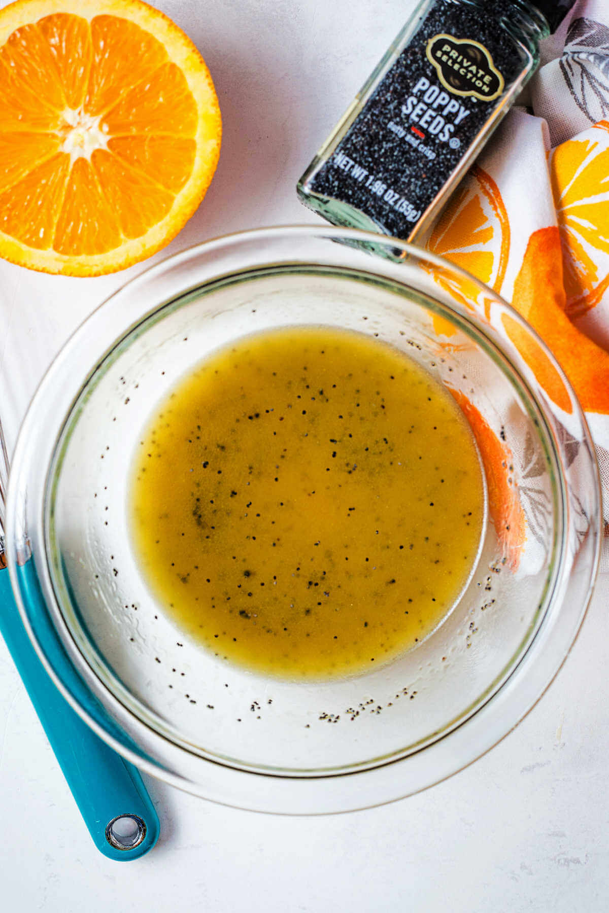 Citrus orange vinaigrette in a glass bowl with a whisk to the side.