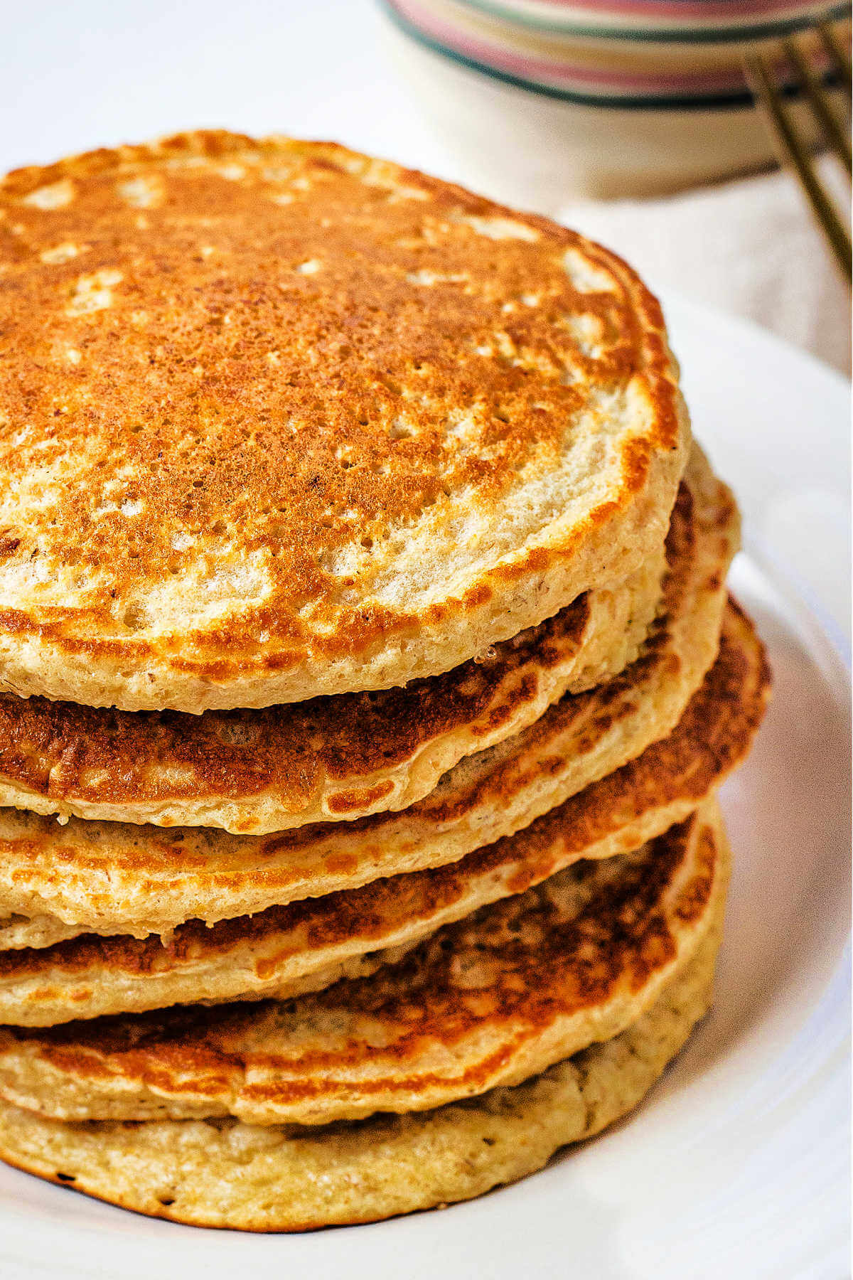 Close up image of a stack of oat flour pancakes on a plate.