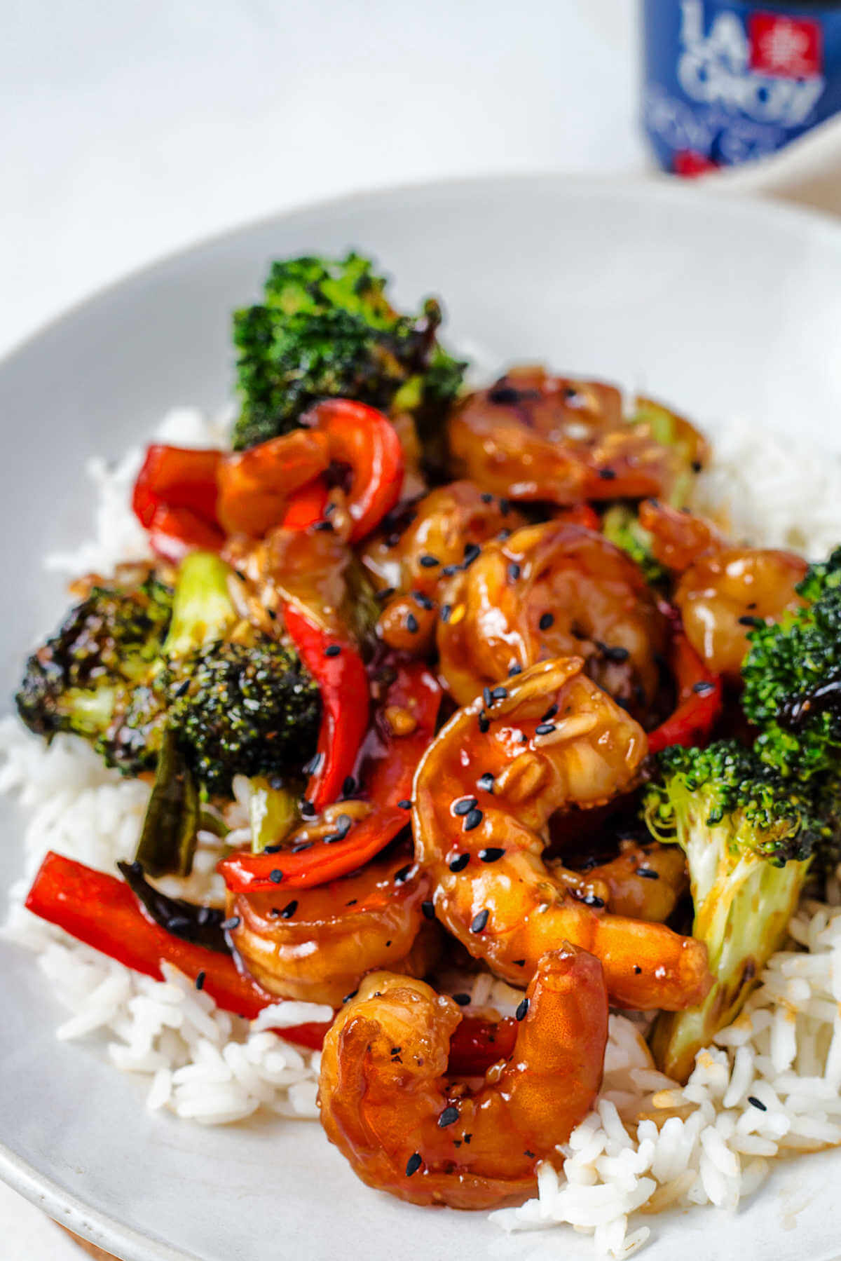 shrimp, broccoli florets, and sliced red bell pepper in a stir fry sauce on a bed of rice.