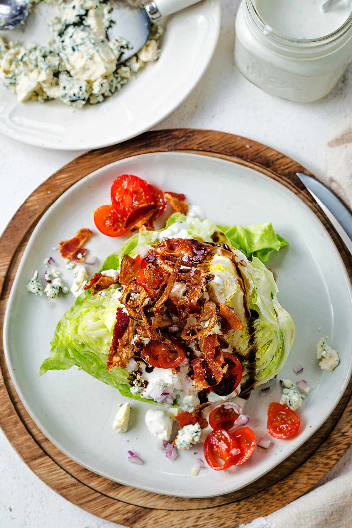 A serving of wedge salad with balsamic drizzled over top on a table.