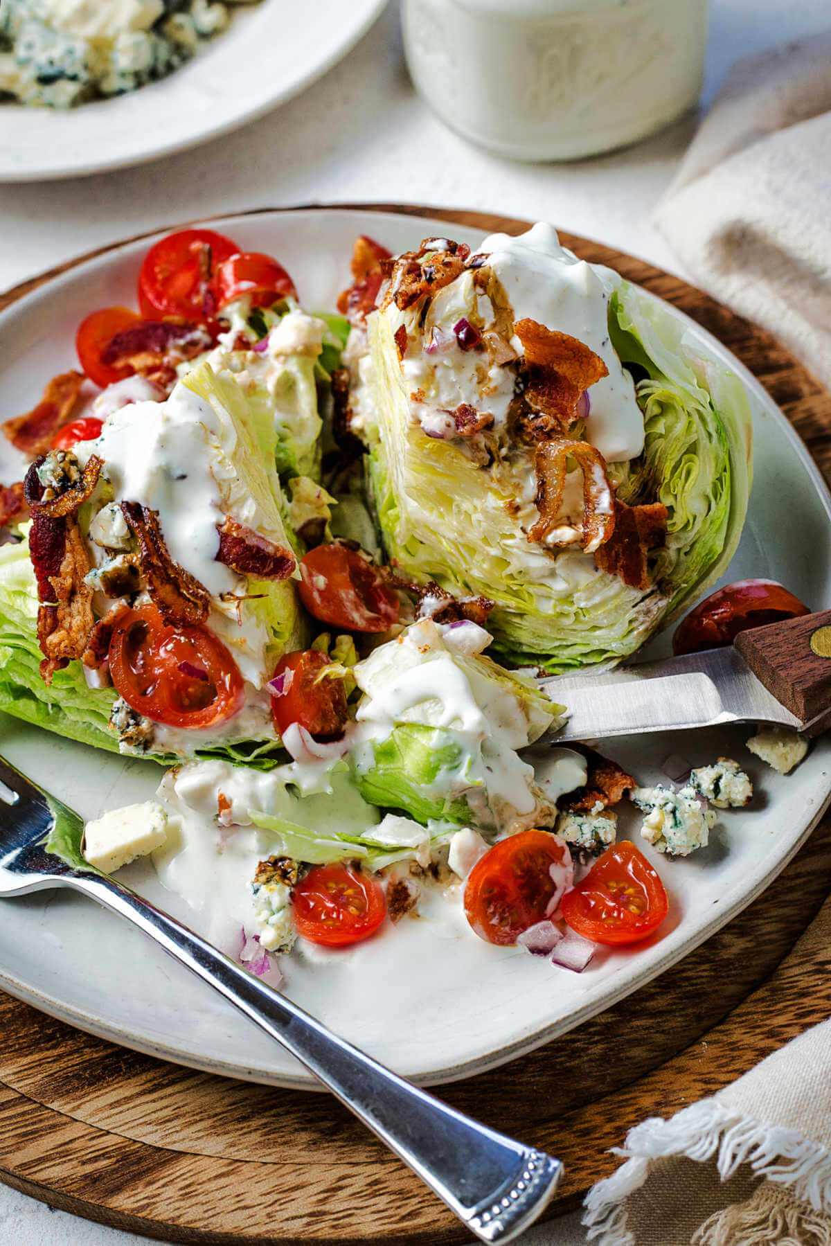 A serving of wedge salad cut into pieces on a plate with a fork and steak knife.
