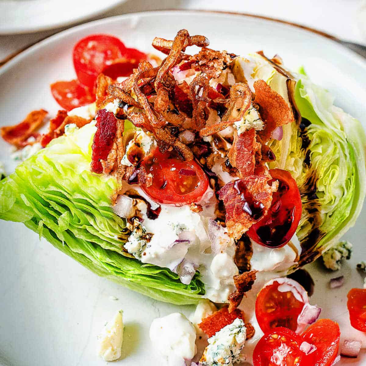 A loaded wedge salad on a plate topped with crispy fried shallots.