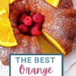 Orange Bundt Cake on a cake stand garnished with raspberries and orange slices.