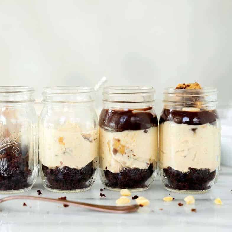 Chocolate Peanut Butter Cheesecake in jars on a table.