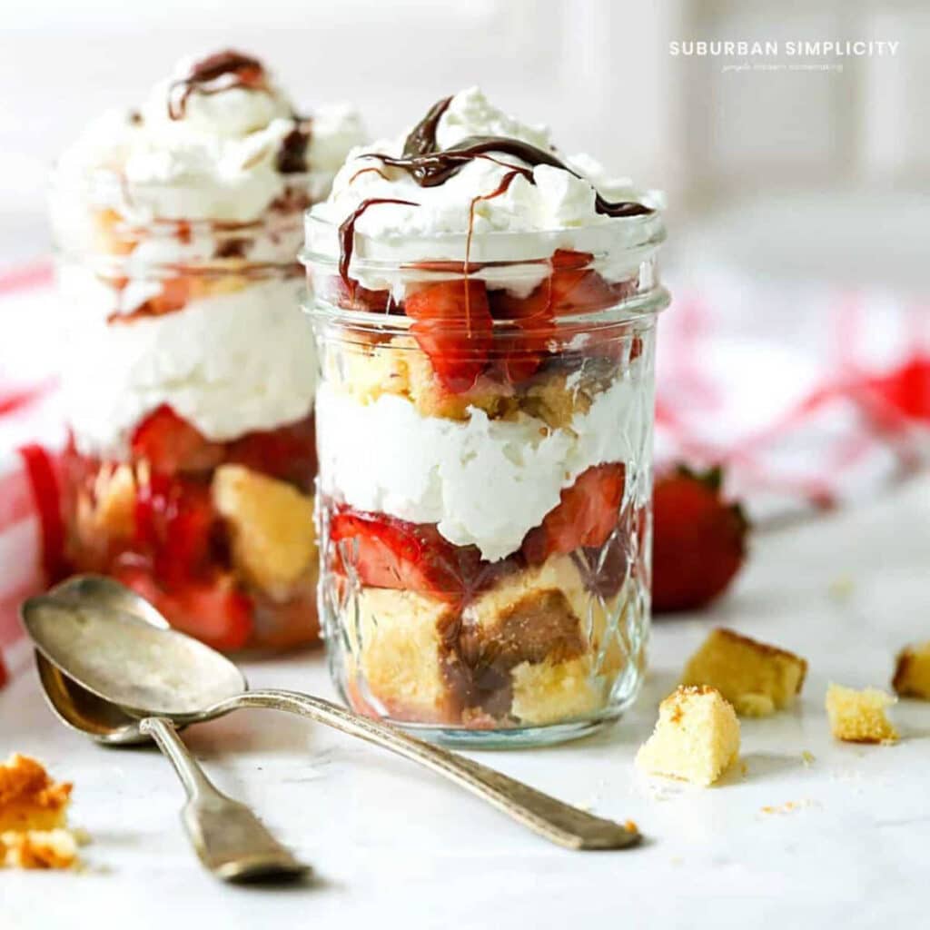 Strawberry Shortcake in a Jar on a table with silver spoons.