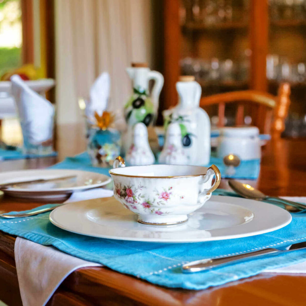 A dining room table set with china and tea cups.