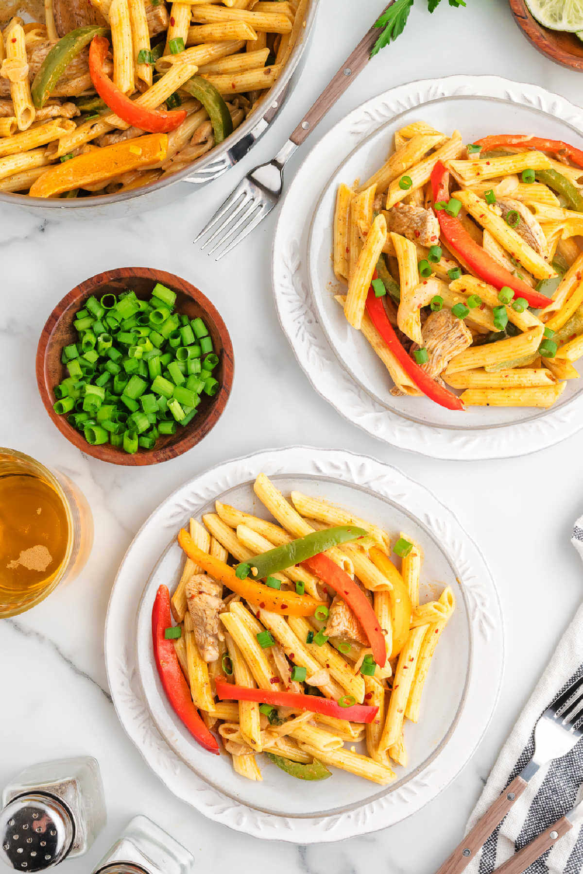 A table set with two bowls of jerk chicken pasta.