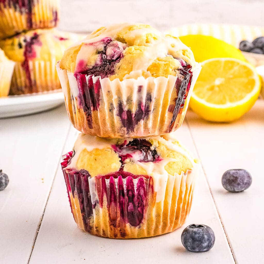 Two lemon blueberry muffins stacked on top of each other on a counter.