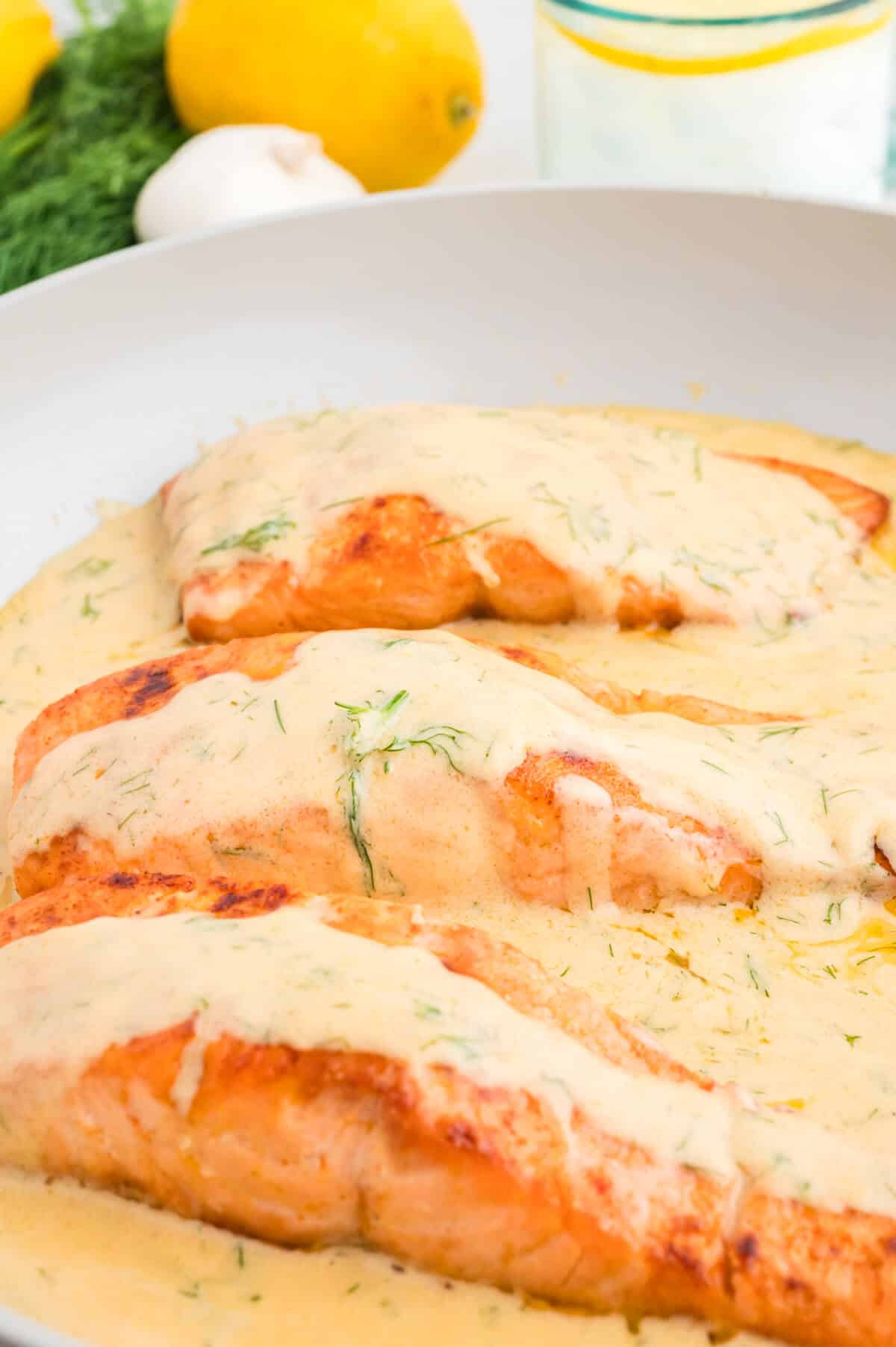 Salmon filets in dill cream sauce in a skillet.