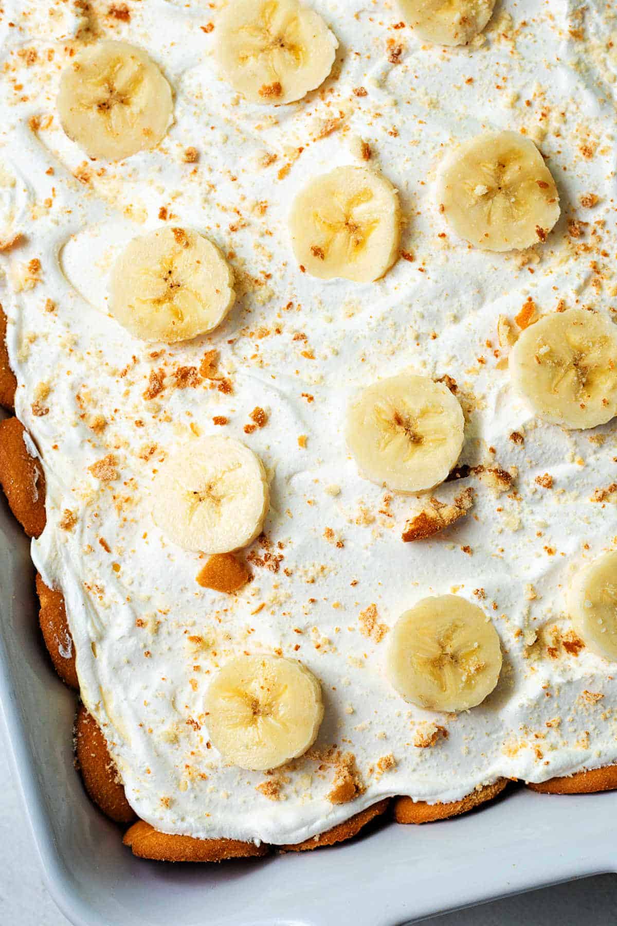 Banana Pudding in a baking dish topped with sliced bananas and crushed wafers.