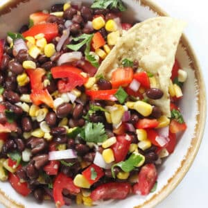 Black Bean Corn Salsa in a bowl with a tortilla chip inserted into the dip.