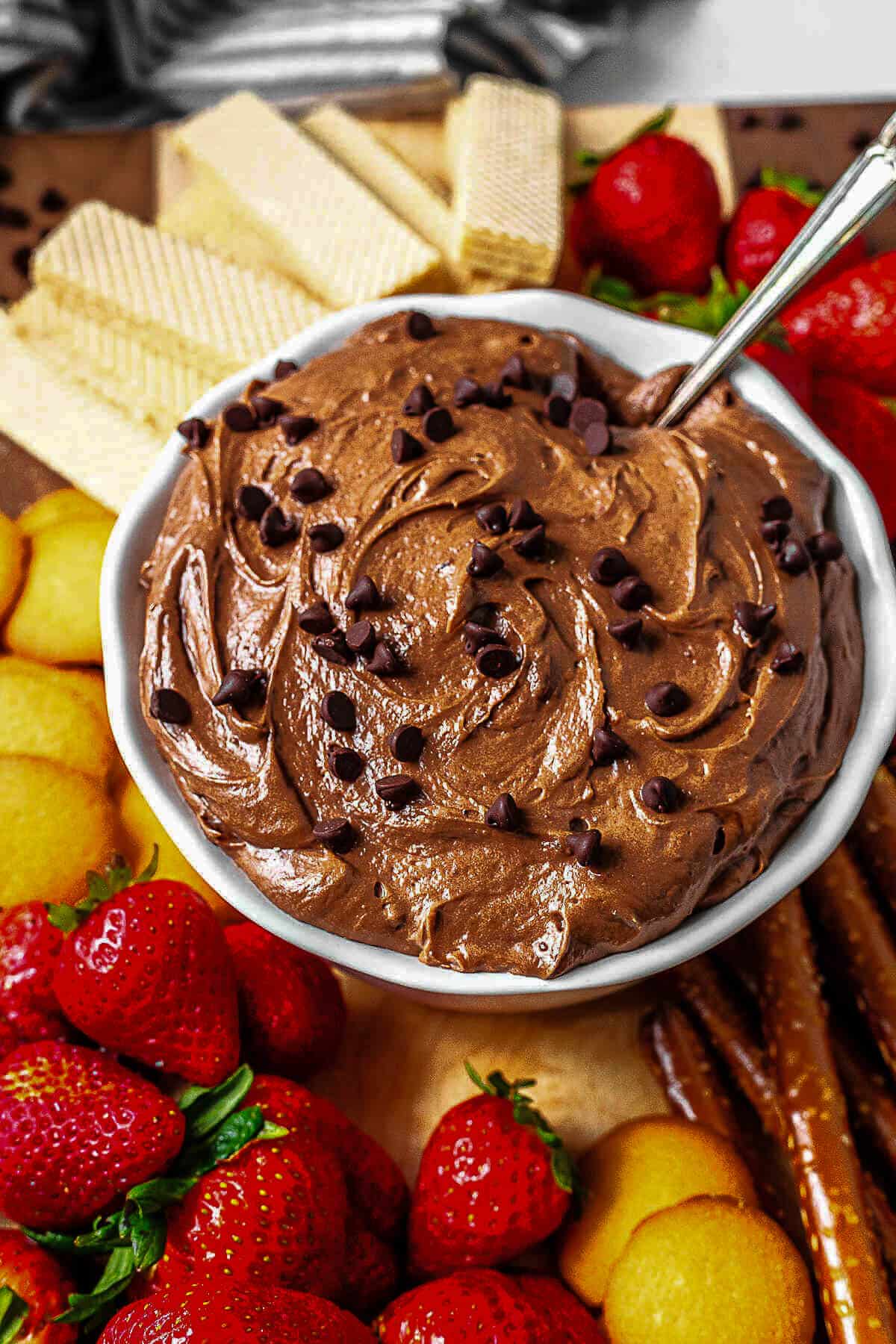 A bowl of brownie batter dip with a spoon inserted into the dip.