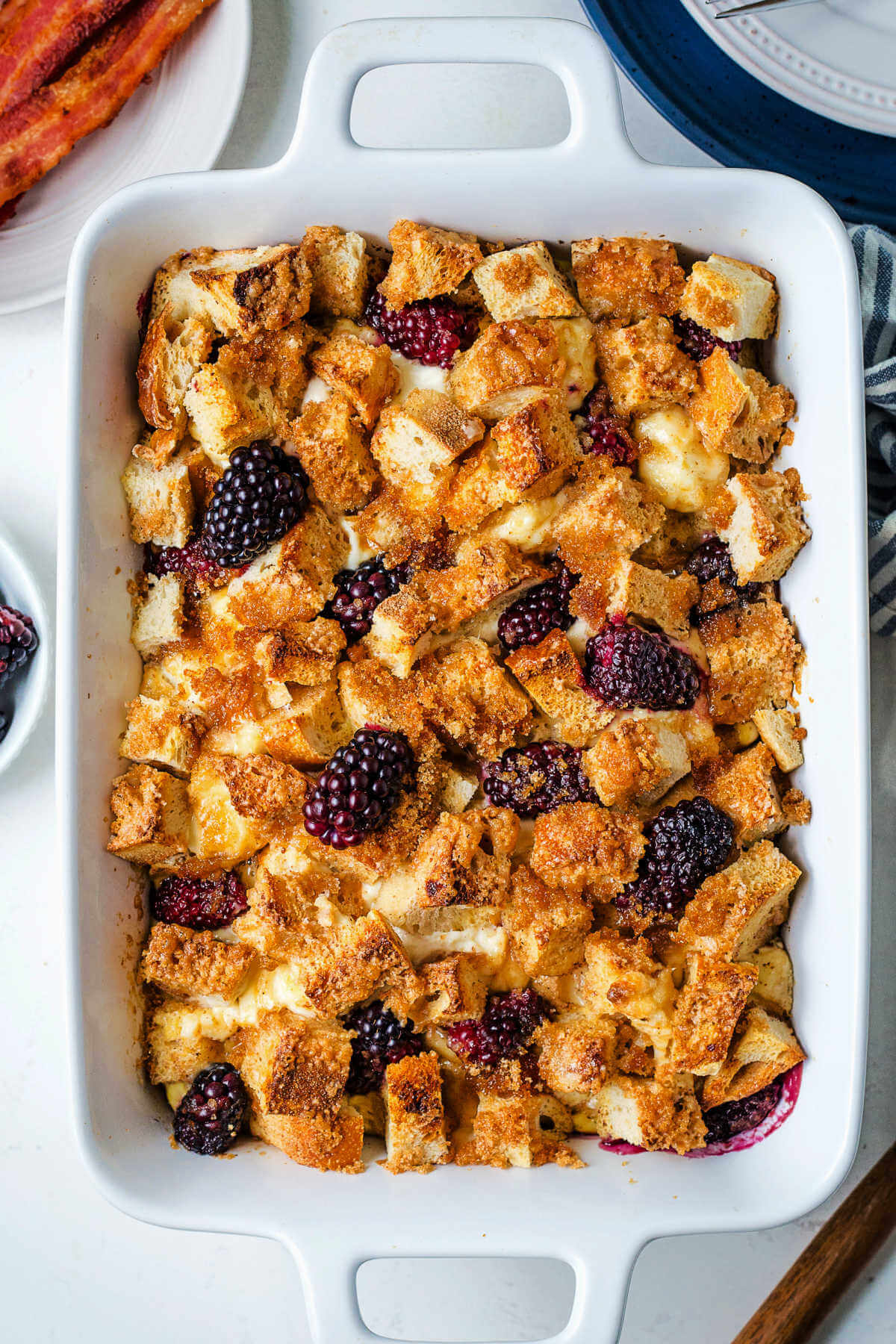 French Toast Bake with cream cheese and blackberries on top in a baking dish on a table.