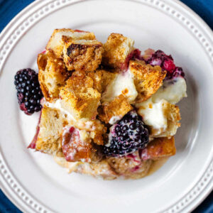 A serving of French Toast Cream Cheese Casserole on a plate with blackberries.