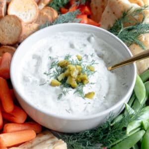 Dill Pickle Dip in a bowl on a platter with fresh veggies.