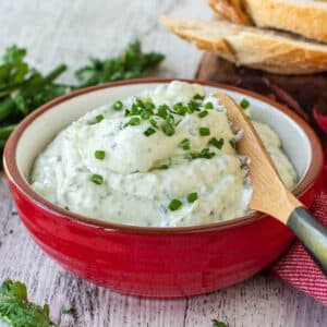 Garlic Herb Cheese Spread in a bowl with a knife on a table.