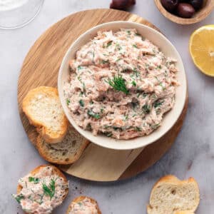 Salmon Rillettes in a bowl with sliced baguette pieces on a table.